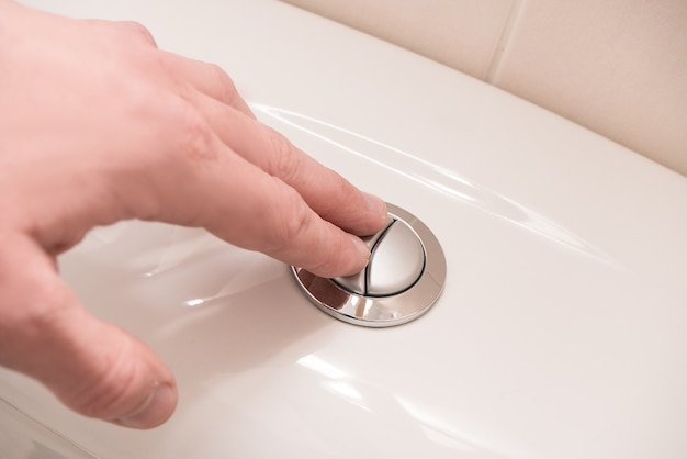 Toilettenspülung. Hand auf den Knopf.