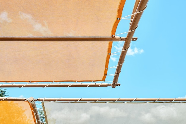 Toldo naranja sobre tumbonas contra el cielo azul claro en el área recreativa del parque acuático en verano