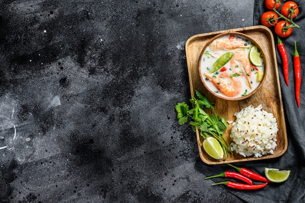 Tom Kha Gai. Sopa cremosa de coco picante com frango e camarão. Comida tailandesa. Superfície preta. Vista do topo. Copie o espaço