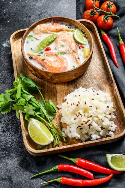 Tom kha gai. sopa cremosa de coco picante com frango e camarão. comida tailandesa. superfície preta. vista do topo