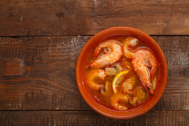 Tom yam sopa con camarones en un plato sobre una mesa de madera Foto horizontal