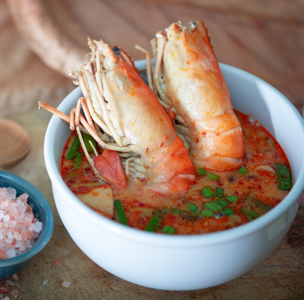 Tom yum kung e condimentos na mesa de madeira