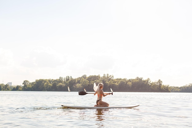 Toma de acción de mujer joven en tabla de paddle