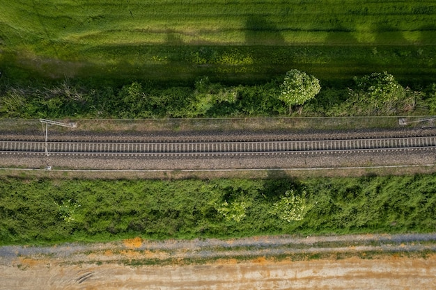 Toma aérea de drones de un ferrocarril entre campos rurales y vegetación