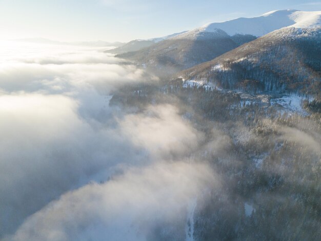 Toma aérea del majestuoso amanecer en las montañas El valle entre las montañas está cubierto de niebla y está iluminado por los cálidos rayos del sol naciente Montañas cubiertas de bosque natural