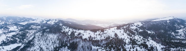 Toma aérea del majestuoso amanecer en las montañas El valle entre las montañas está cubierto de niebla y está iluminado por los cálidos rayos del sol naciente Montañas cubiertas de bosque natural