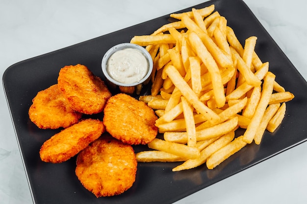Una toma de ángulo alto de un plato de papas fritas y pollo frito