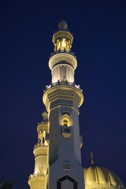 Toma en ángulo bajo de Madina Minar iluminada en Emiratos Árabes Unidos por la noche