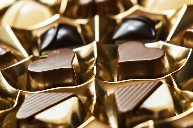 Toma de detalle de dos chocolates en forma de corazón en su caja dorada. Día Internacional del Chocolate.