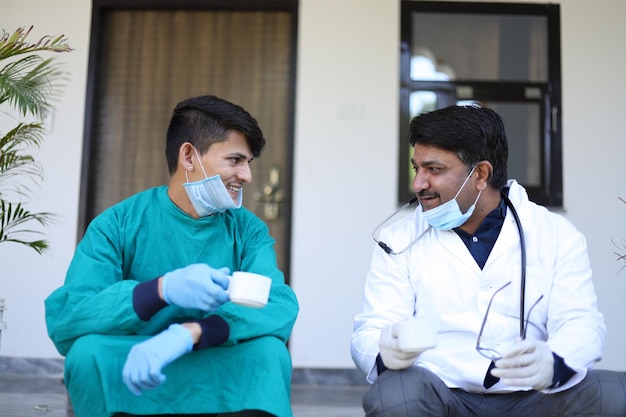 Toma de enfoque poco profunda de un médico indio y un trabajador de la salud con mascarillas en la barbilla