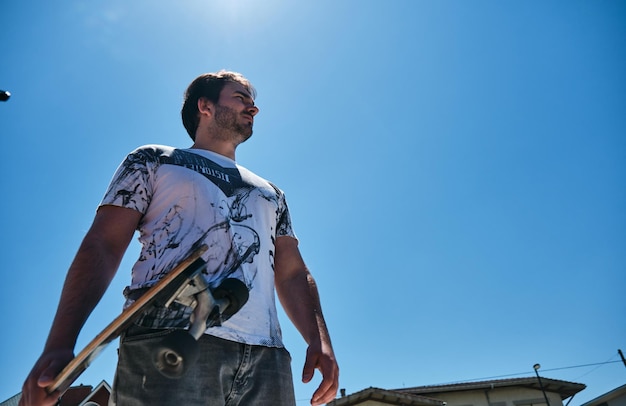 Toma épica desde abajo de un patinador bajo un cielo azul soleado