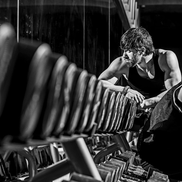 Toma en escala de grises de un hombre caucásico musculoso atlético en forma haciendo ejercicio en el gimnasio