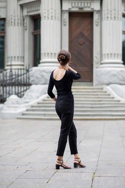 Foto toma de estilo de vida de una joven romántica con el pelo corto viste un traje de moda mirando al antiguo edificio histórico