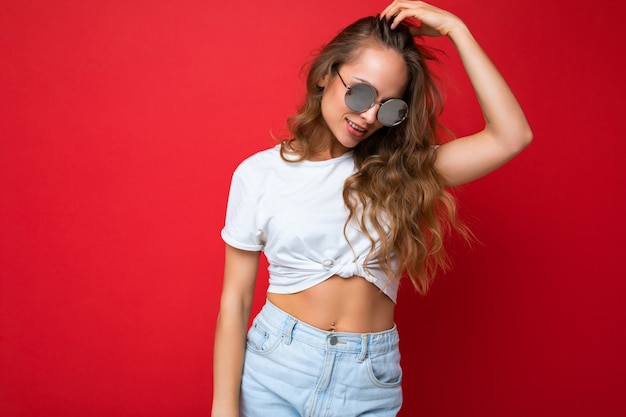 Toma de la foto de la hermosa joven rubia oscura con ropa casual y elegantes gafas de sol