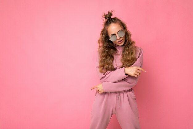 Toma de la foto de la hermosa joven rubia oscura con ropa casual y elegantes gafas de sol