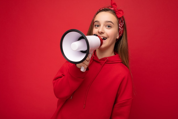 Toma de la foto de la hermosa niña rubia oscura sonriente feliz positiva bastante agradable con sincero