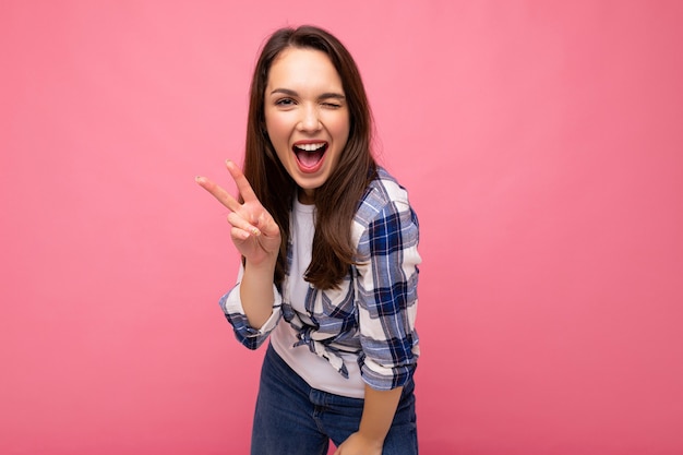 Toma de la foto de la joven mujer bonita morena sonriente encantadora positiva con emociones sinceras vistiendo