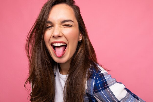 Toma de la foto de linda agradable encantadora hermosa atractiva bastante joven mujer feliz vistiendo ropa elegante aislada sobre fondo colorido con espacio de copia que muestra la lengua y divertirse.