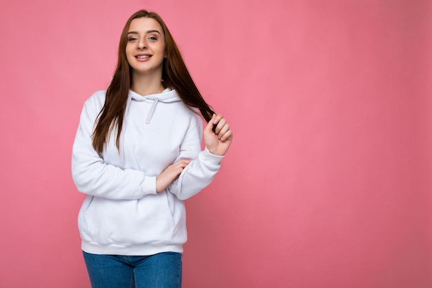 Toma de foto de mujer joven sonriente bastante alegre vistiendo ropa casual de moda que se encuentran aisladas sobre fondo de colores con espacio de copia mirando a la cámara y divirtiéndose