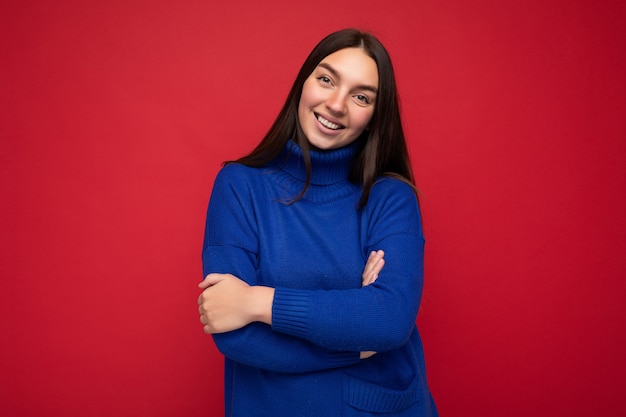 Toma de la foto de la persona del sexo femenino joven sonriente bastante alegre que se encuentra aislada en el fondo colorido con el espacio de la copia que mira la cámara y que se divierte.