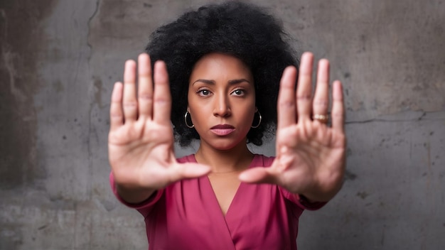 Foto la toma horizontal de una mujer afroamericana seria muestra el gesto de detención extendiendo las palmas hacia la cámara