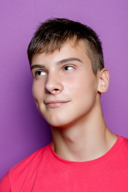 Toma interior de chico guapo musculoso con expresión positiva, viste una camiseta blanca de maqueta informal para su promoción, se destaca sobre un fondo púrpura, espacio libre a un lado. Personas y emociones. sonrisa