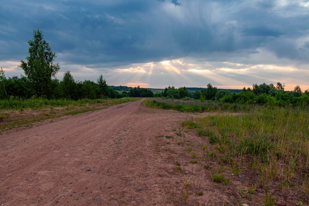 Toma panorámica de un camino rural que conduce al cielo del amanecer...