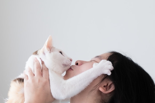 Toma de primer plano de una mujer asiática sosteniendo un gato y besos.