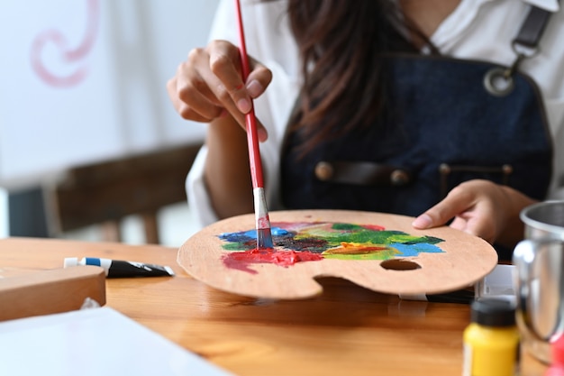 Foto toma recortada artista mujer mezcla de colores en la paleta.