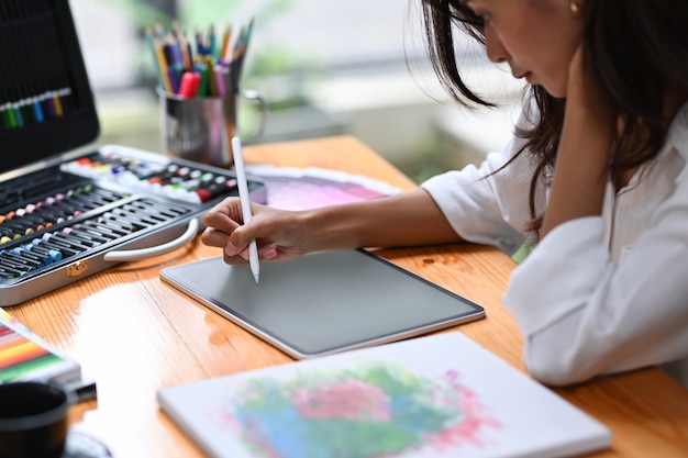 Toma recortada Artista mujer trabajando con tableta digital en su taller.