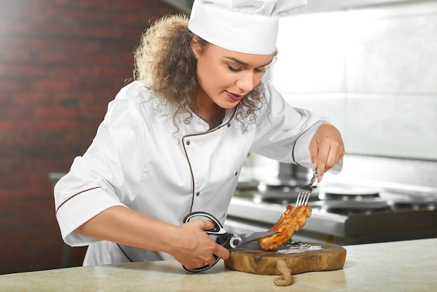 Toma recortada de una cocinera preparando un delicioso filete de pollo a la parrilla en su cocina cortándolo con unas tijeras