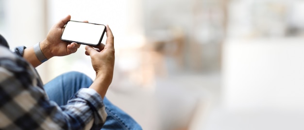 Foto toma recortada del empresario que usa un teléfono inteligente horizontal que incluye una pantalla de trazado de recorte en un fondo borroso con espacio de copia