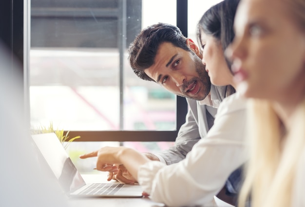 Toma recortada de empresarios con tabla gráfica y computadora portátil, tableta discutiendo sobre el plan de negocios juntos en la oficina moderna.