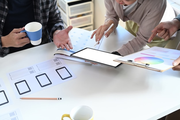 Foto toma recortada del equipo de diseñador usando tableta digital y haciendo una lluvia de ideas sobre el diseño de color en la agencia de diseño.