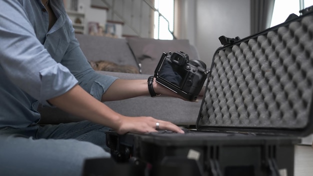 Toma recortada del fotógrafo masculino poniendo una cámara digital en una bolsa grande con otros dispositivos.