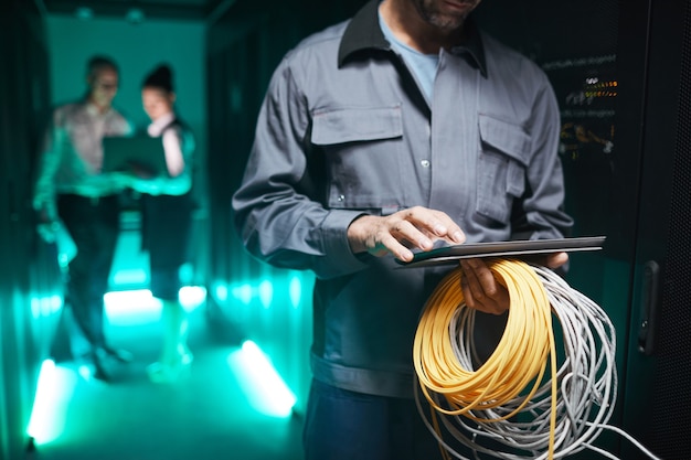 Toma recortada del ingeniero de redes con tableta digital en la sala de servidores durante el trabajo de mantenimiento en el centro de datos, espacio de copia