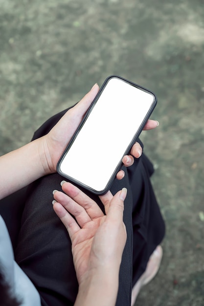 Toma recortada de la mano de la mujer que sostiene el teléfono inteligente de pantalla en blanco, vista vertical.