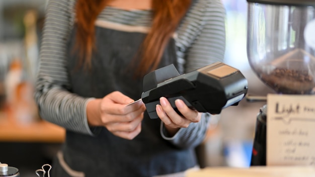 Toma recortada Mujer barista sacando tarjeta de crédito del terminal de pago pago sin contacto