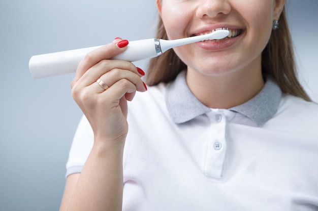 Toma recortada de una mujer dentista mostrando con cepillo de dientes eléctrico