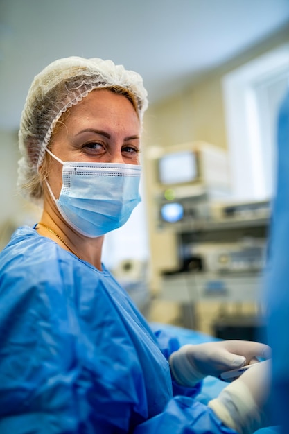Toma de retrato de una enfermera mirando a la cámara durante la operación en el quirófano Médicos profesionales que realizan cirugía