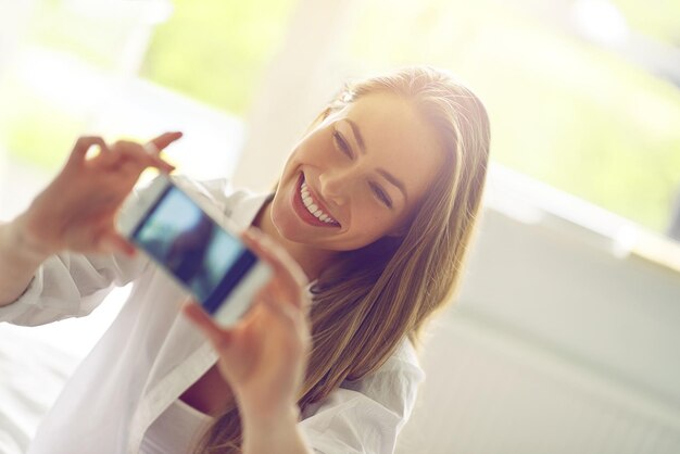 Toma de selfies del domingo por la mañana de una mujer joven que se toma una selfie matutina en su dormitorio