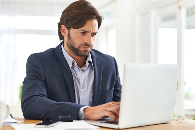 Se toma en serio su trabajo. Un hombre de negocios atractivo trabajando duro en su computadora portátil.