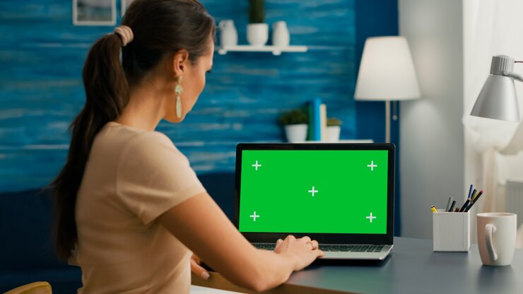 Foto toma trasera de freelencer que trabaja en un proyecto de marketing usando una pc aislada con una maqueta de pantalla verde chroma key. mujer escribiendo en el ordenador portátil sentado en el estudio de la oficina en casa