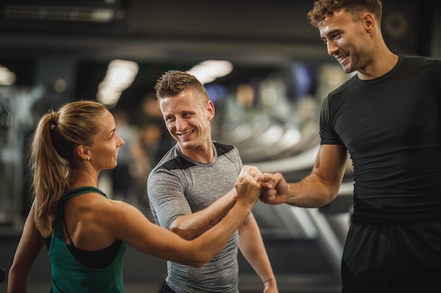 Toma de tres jóvenes uniendo sus puños en solidaridad en un gimnasio.