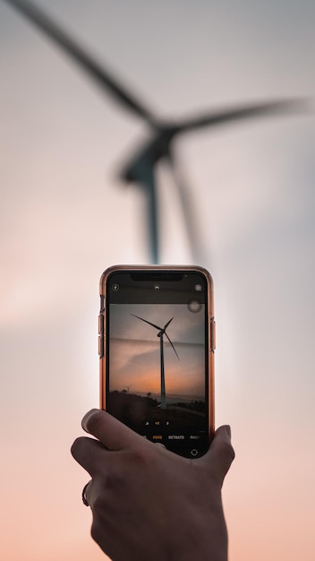 Toma vertical de un teléfono tomando una fotografía de una turbina eólica