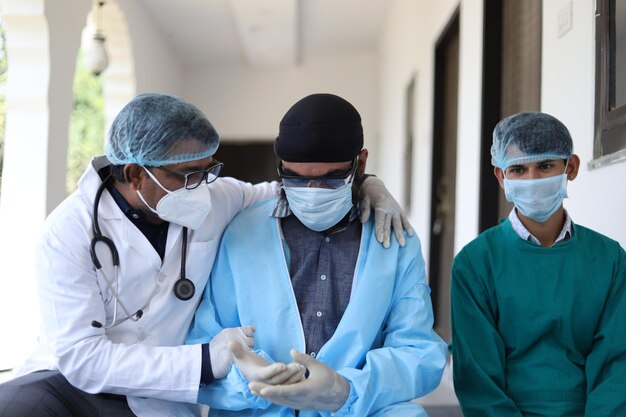 Una toma vertical de tres médicos indios con uniforme médico y máscara en el fondo de la clínica