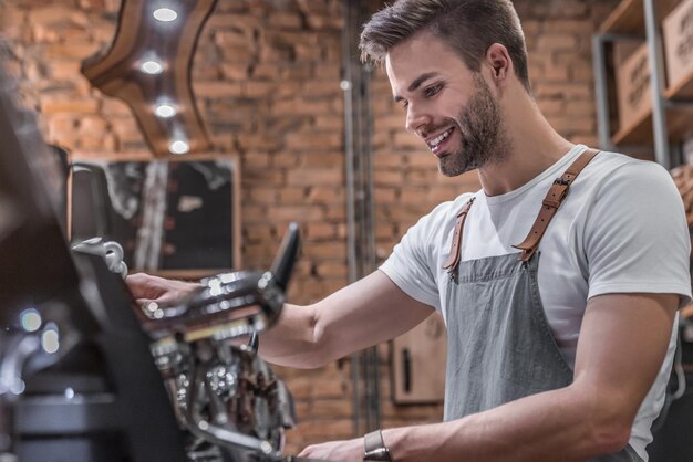 Toma de vista lateral de un barista masculino haciendo una taza de café