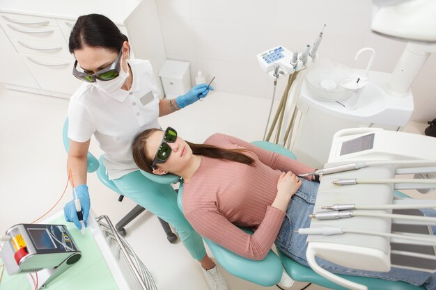 Toma de vista superior de una paciente recibiendo tratamiento dental por su dentista en la clínica