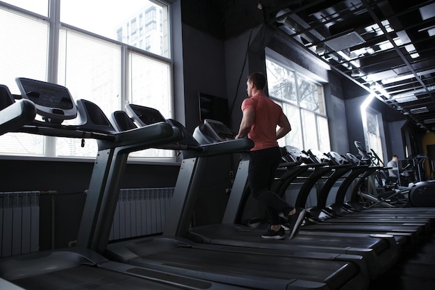 Toma de vista trasera de cuerpo entero de un deportista musculoso corriendo en un espacio de copia de cinta de correr