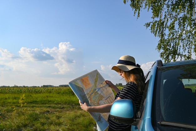 Toma de vista trasera de una pareja conduciendo por una carretera rural Mujer sosteniendo un mapa y mostrando el mapa de ruta a su novio conduciendo el coche Pareja en un viaje por carretera